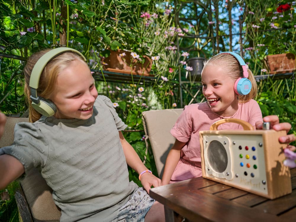 hörbert est posé sur une table de jardin, et deux filles écoutent avec des casques Bluetooth